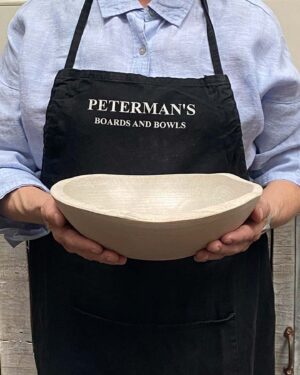 A 10-inch White Pearl Oak oval bowl held by a Spencer Peterman employee, finished in a pale, luminous wash that softens the grain.