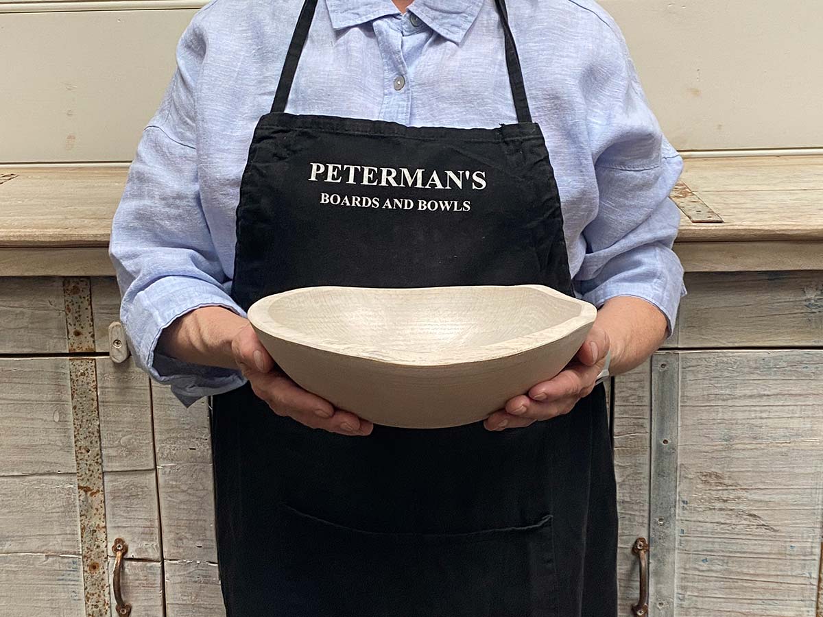 A 10-inch White Pearl Oak oval bowl held by a Spencer Peterman employee, finished in a pale, luminous wash that softens the grain.