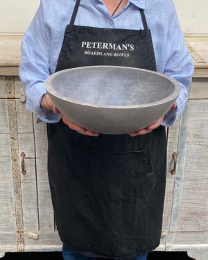 A 13-inch Driftwood Oak round bowl held by a Spencer Peterman employee, featuring the pale, matte finish of aged oak.