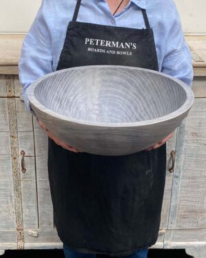 An employee at Spencer Peterman holding a 15-inch Driftwood Oak round bowl, showcasing the soft matte finish and organic grain of aged oak.