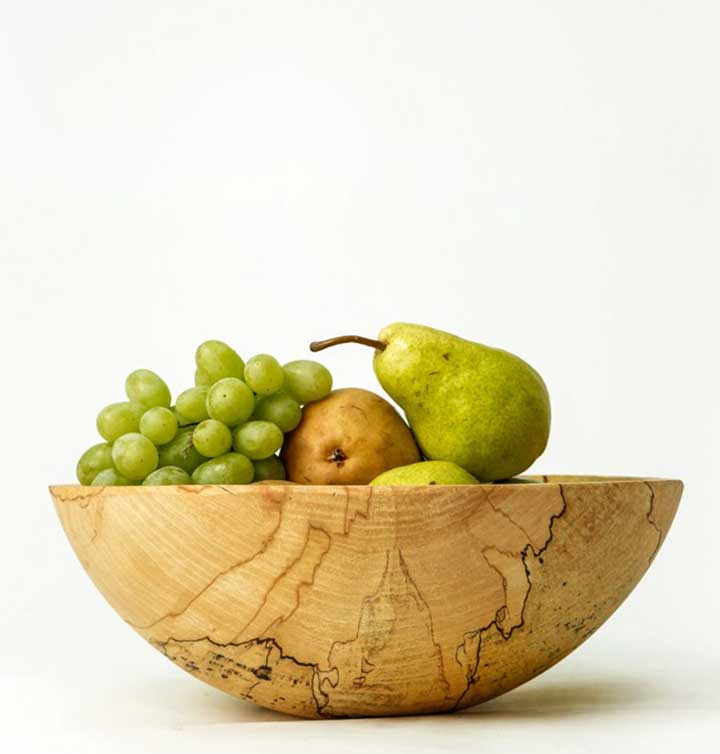 A spalted maple wooden bowls with dramatic dark lines and organic patterns hold fruit