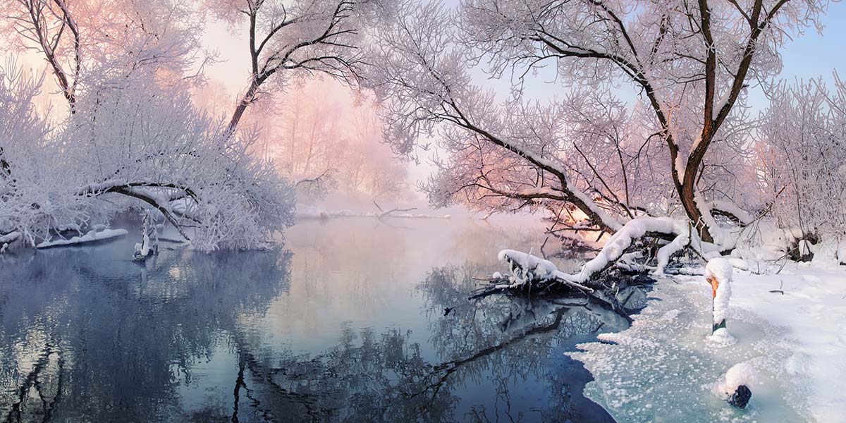 Snow-covered New England woods along a quiet river in winter