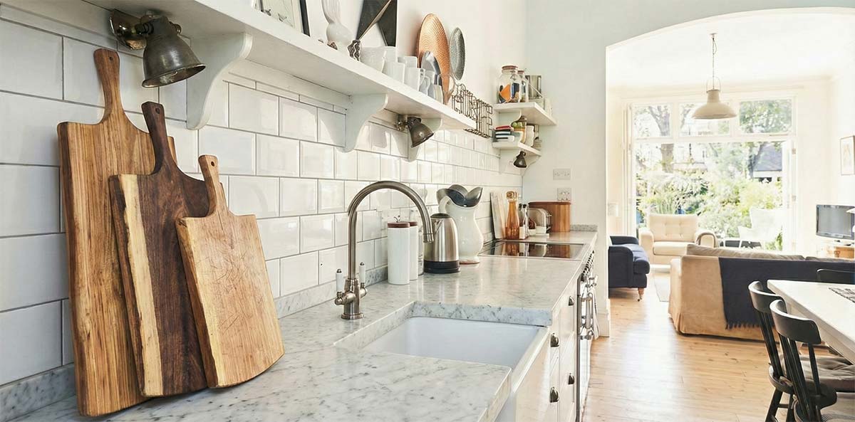 Wooden cutting boards leaning against a tiled kitchen backsplash in natural daylight