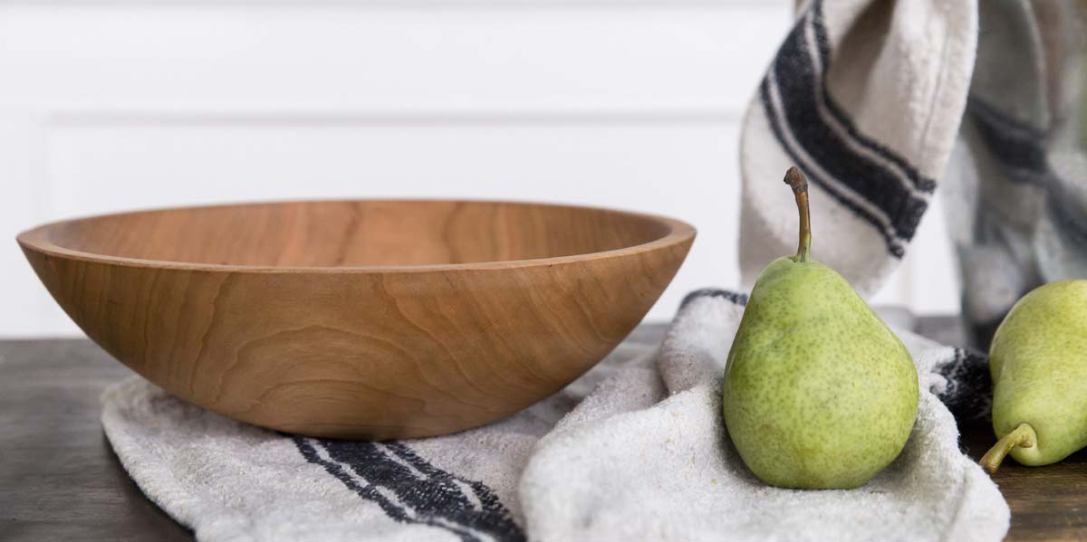 Wooden bowl and green pears on a linen cloth, styled simply for an everyday winter table