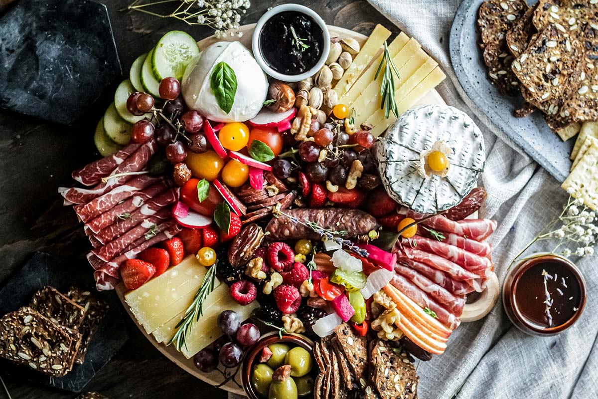 Large charcuterie board idea with cured meats, soft cheese, fruit, nuts, and crackers