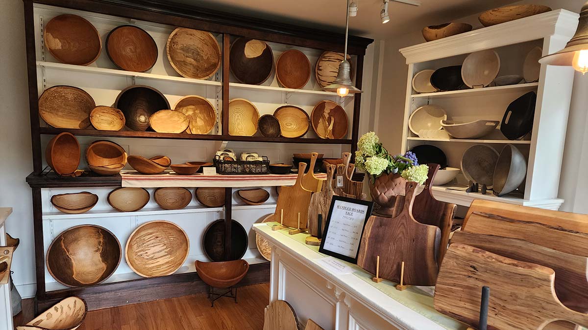 Interior gallery display of handcrafted wooden bowls and cutting boards on shelves