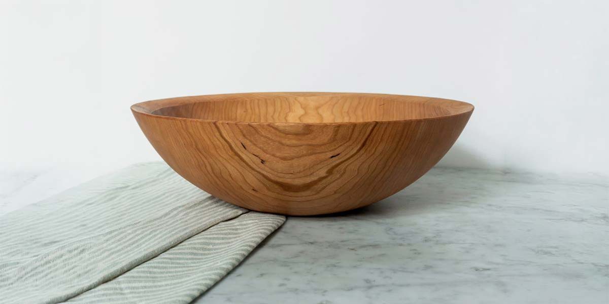 Cherry wooden bowl with warm reddish tone and smooth curved grain on a countertop