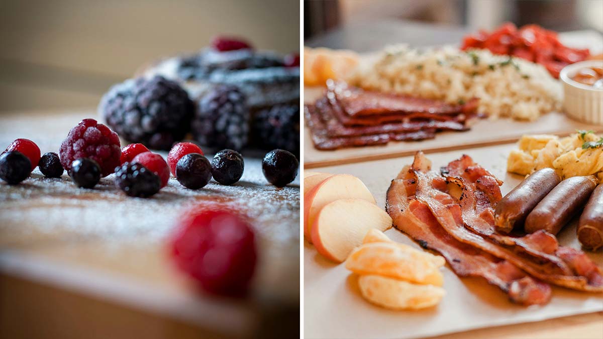 breakfast charcuterie board with waffles, berries, bacon, and sausage arranged on a wooden board