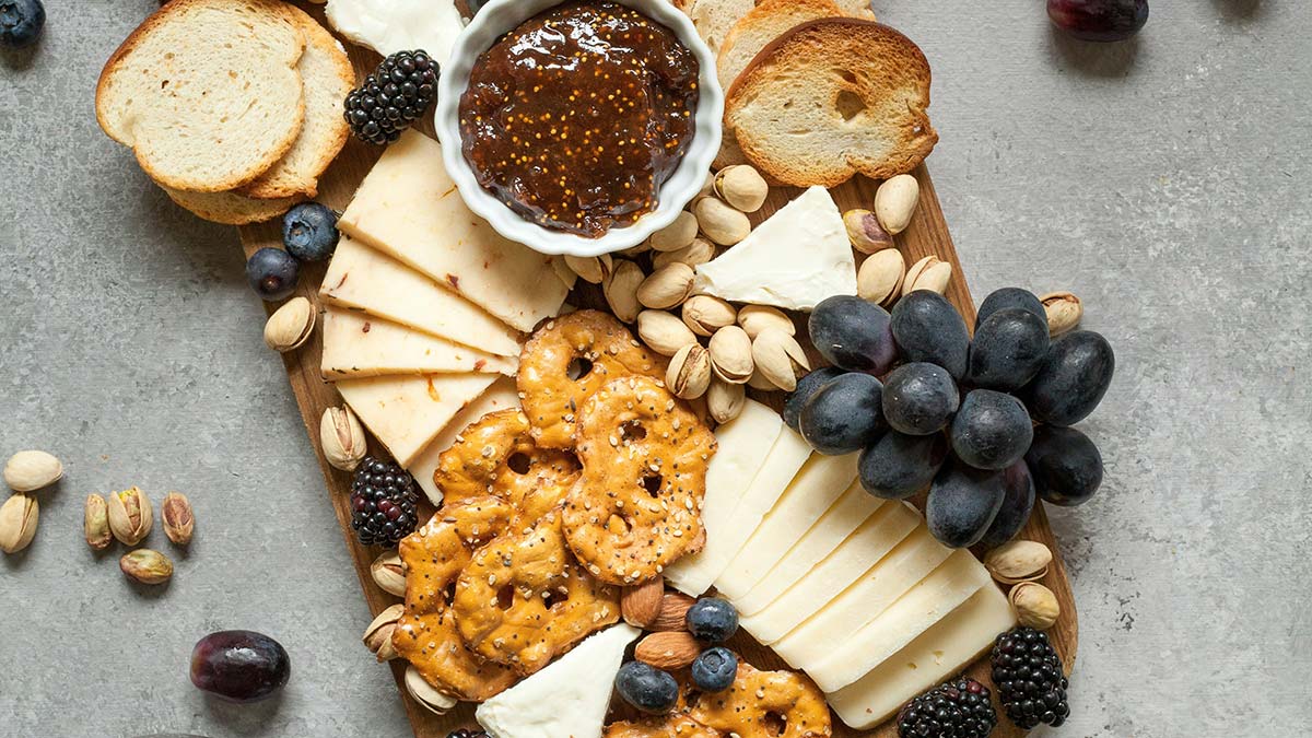 charcuterie board with cheese, crackers, grapes, and fig jam on a wooden board
