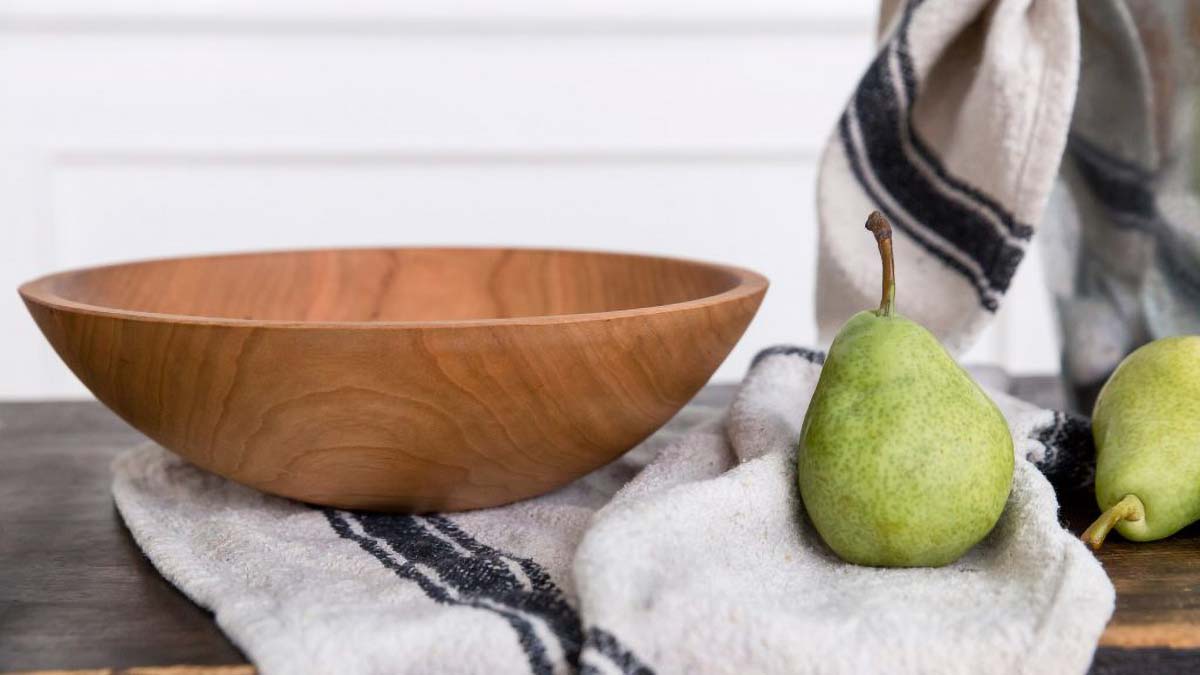 Heirloom gifts for mom cherry wooden bowl resting on a folded cloth with fresh pears nearby